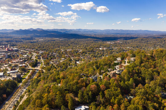 Rural homes overlooking colorful mountain forests near Asheville, North Carolina. Peak autumn foliage creates breathtaking landscape around peaceful community.