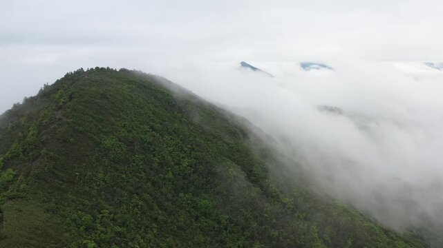 Lush green mountain peaks covered by thick rolling clouds in a misty landscape with mountain landscape wilderness