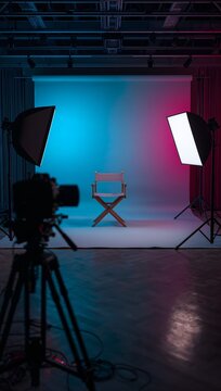 A professional photography studio features a minimalist chair illuminated by dramatic cyan and magenta lighting.