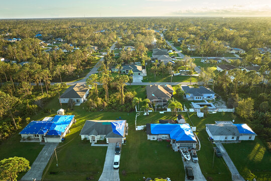 Top view of leaking house roofs covered with protective tarp sheets against rain water leaks until replacement of asphalt shingles. Damage of building rooftop as aftermath of hurricane Ian in Florida