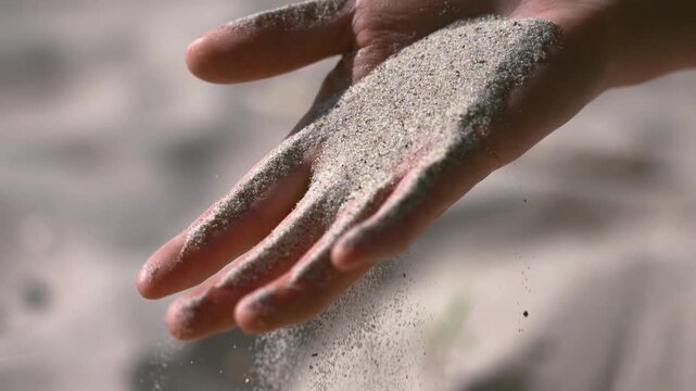 Hand holding and pouring soft fine beach sand through fingers with vacation seashore shoreline particle relaxing
