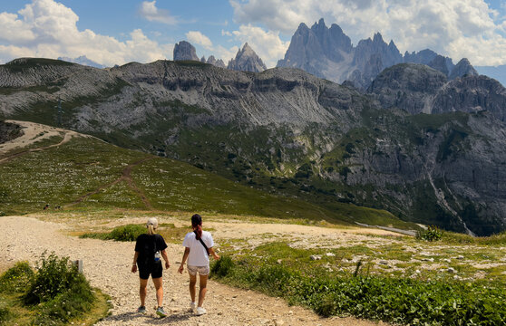 People hiking a mountain trail with backpack in summer Dolomites Italy