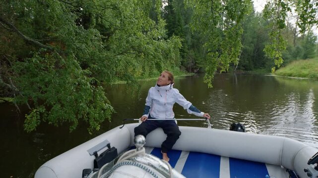 Woman steers the vessel on the wild river and passes by the picturesque place