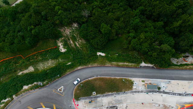  aerial view of urban roundabout with roads and green spaces in neutral setting, showing asphalt, grass, and concrete materials under natural light.
