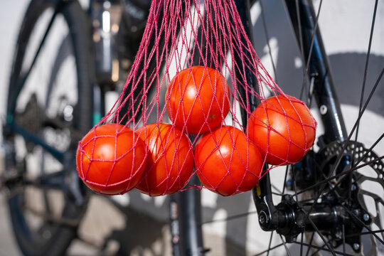 Fresh Tomatoes in a Mesh Bag Hanging from a Bicycle
