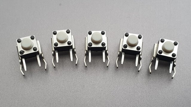 Row of Five Small Tact Switches Electronic Components on Grey Background