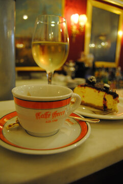 Rome, Italy &ndash; October 10, 2014. Coffee cup, glass of white wine and cake at Caffe Greco cafe in Rome.