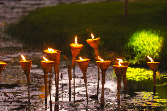 Flame torch bamboo wicker fire light water reflection garden night decorative outdoor torch with warm flame beside wet ground and grass after rain