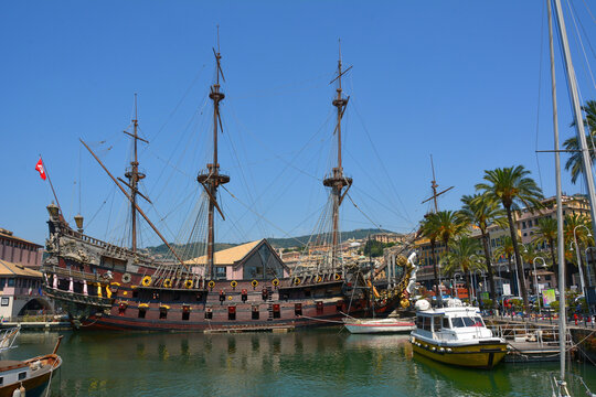 Genoa, Italy &ndash; July 9, 2015. Full-size replica of pirate ship Il Galeone Neptune in Genoa. View with boats, historic buildings and palm trees.
