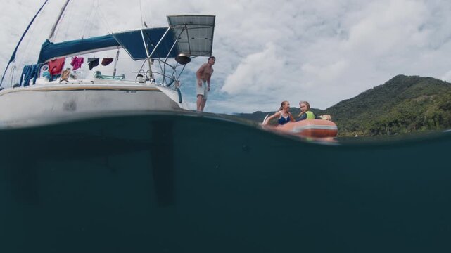 Splitted underwater view of the sailing boat with family with kids on it