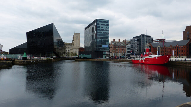 Liverpool, Great Britain &ndash; June 26, 2014. Modern architecture and historic lightship at Canning Dock in Liverpool, England. View with vessels and reflections in water.