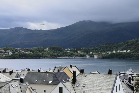 Alesund city roofs, ocean bay and surrounding mountains, Norway. Scandinavian cityscape with traditional coastal houses.