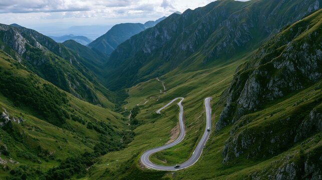 Switchback road snakes through a deep alpine valley surrounded by steep green mountain slopes.