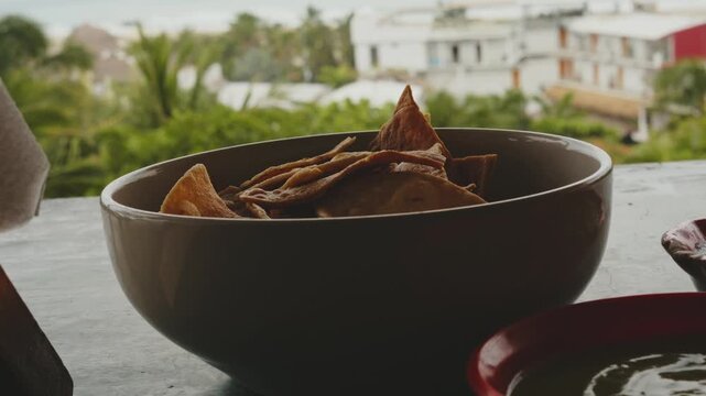 Delicious corn nachos served in a bowl on a terrace overlooking a tropical coastal town and the sea