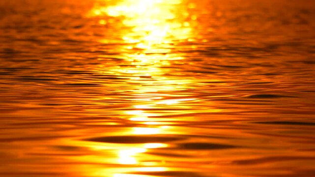 Golden sunlight glows on ocean waves while constant motion creates a hypnotic pattern across the expansive surface. Static long shot.