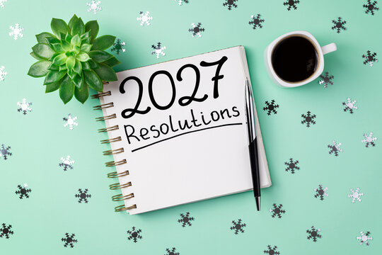 New year resolutions 2027 on desk. 2027 goals list with notebook, coffee cup, plant on blue table. Resolutions, plan, goals, action, checklist, idea concept. New Year 2027 resolutions, copy space