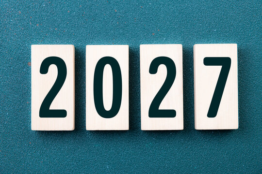 2027 Happy New Year. Wooden cube block 2027 greeting card on green. Concept 2027 New Year background. Business, resolutions, goals, inspiration, success, ideas
