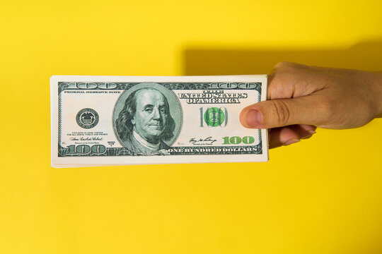 Hand holding stack of hundred dollar bills