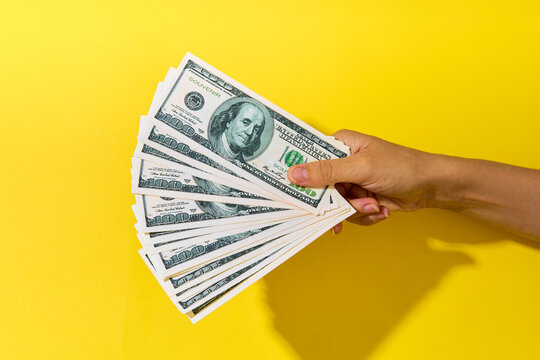 Hand holding fan of hundred dollar bills