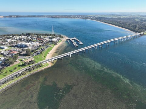 San Remo, Victoria, Australia - 28 June 2026: Aerial view of San Remo Bridge spanning the channel to Phillip Island, with boats at the pier, coastal vegetation, and clear blue water.