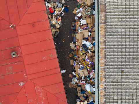 Belgrade, Serbia - 12 November 2025: Aerial view of discarded cardboard boxes and wooden crates piled in a narrow passage between market buildings.