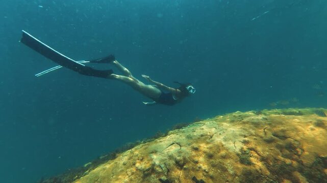 Young slim woman swims underwater, freediving and snorkeling in the sea near the coral reef near the island of Ilha Grande in Brazil