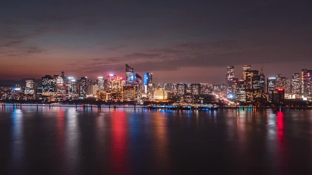 Aerial twilight skyline of Hangzhou Qianjiang New Town, illuminated modern skyscrapers and Grand Theater, city lights reflect on Qiantang river