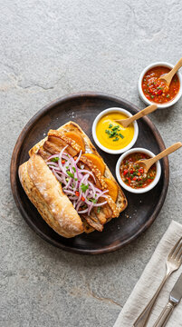 Peruvian Pan con Chicharr&oacute;n on Neutral Stone Surface, Top View Minimal Food Photography