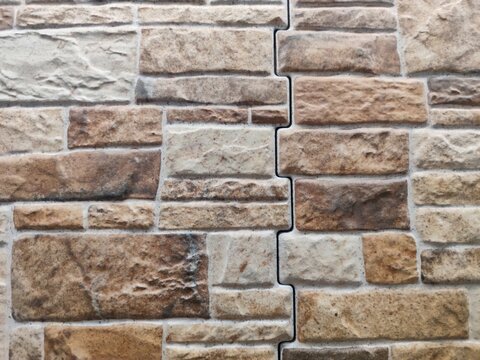 Stacked stone tiles background with interlocking puzzle joint brick masonry panels
