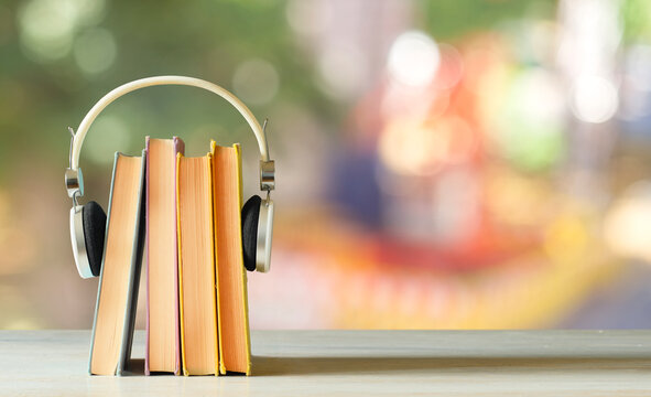 audiobooks concept with stack of books and headphones on blurred nature background,free copy space