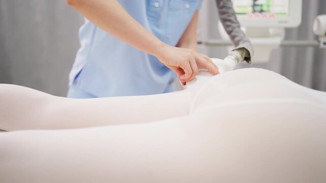 Professional beauty therapist performing vacuum roller massage on female client in aesthetic clinic, using modern body treatment equipment for skincare, wellness and body contouring