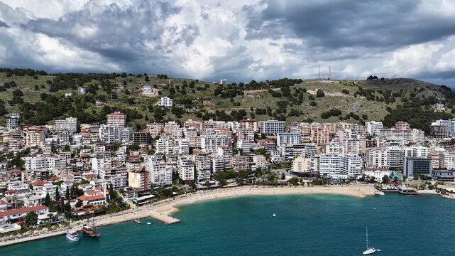 Saranda, Albania. Aerial 4K panoramic drone view of the Ionian Sea, port, boats and Mediterranean urban architecture. Majestic view of the resort town and its beaches.