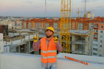 Construction worker pointing upwards at building site with cranes and cityscape © nazariykarkhut