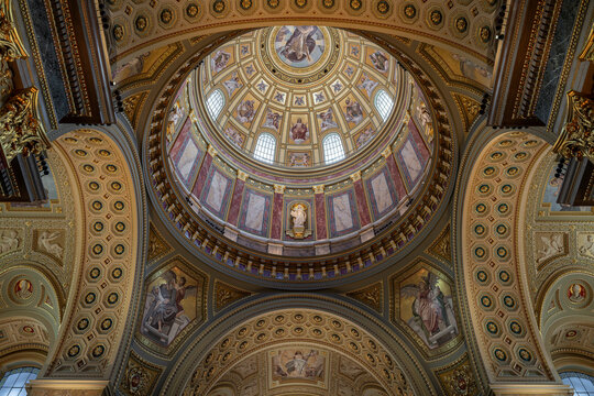 Wide upward view of the coffered dome interior with mosaic saints and gilded panels inside Saint Stephen's Basilica in Budapest