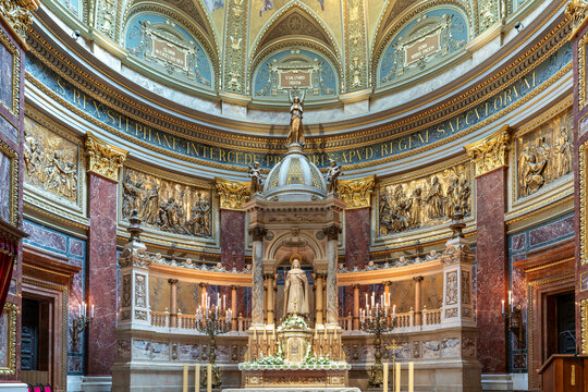 Wide view of the sanctuary apse with bronze reliefs and the main altar statue of Saint Stephen in Budapest