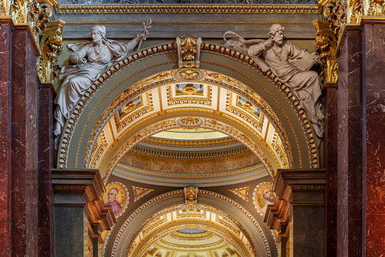 Sculpted figures atop a marble archway framing a domed vista inside Saint Stephen's Basilica in Budapest, Hungary