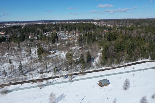 Aerial winter view of a snowy forest with cottages and a distant town