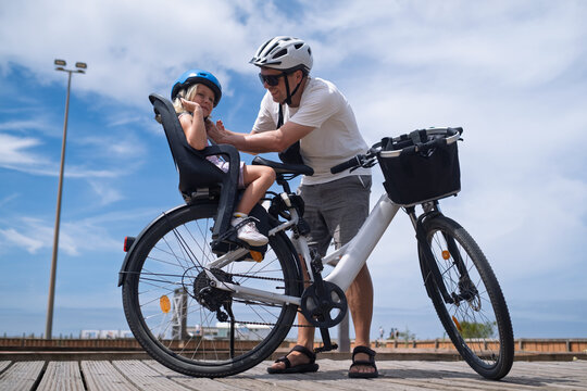 Father Preparing to Ride a Bicycle with His Daughter in a Child Seat