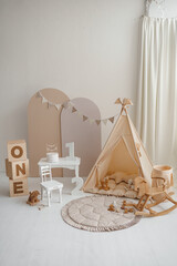 Neutral beige kids studio interior with wigwam tent, ONE blocks and rocking horse for birthday © Minakryn Ruslan 