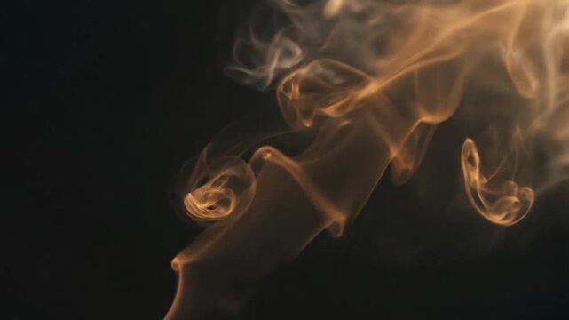 Golden smoke plumes rising and swirling gracefully against a dark background