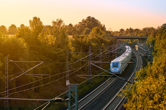 Intercity train traveling through a scenic railway corridor at sunset, surrounded by trees and overhead power lines. Stuttgart to Mannheim, Baden-W&uuml;rttemberg, Germany