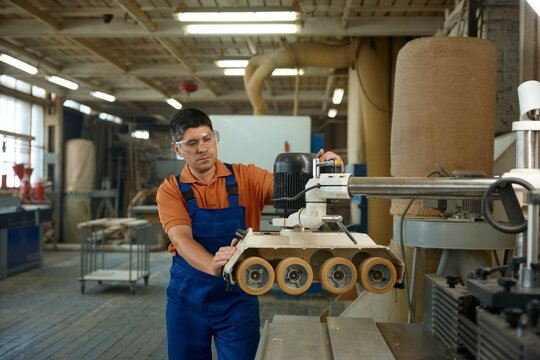 Carpenter adjusting machine settings to ensure consistent thickness and quality of timber