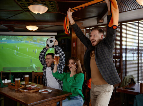 Friends cheer enthusiastically at pub. Lively pub scene with friends celebrating match