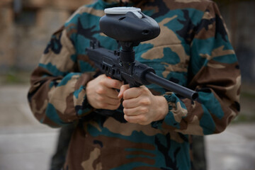 Fototapeta premium A soldier, wearing military clothes is holding a weapon in his hands