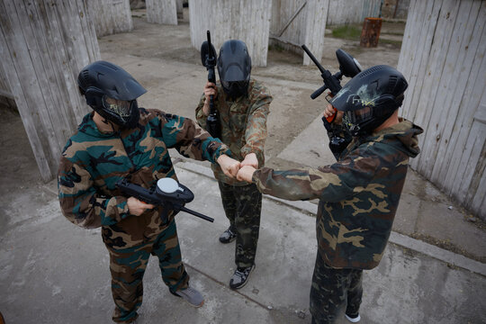 An armed group of several soldiers make a commanding gesture as they prepare on training field