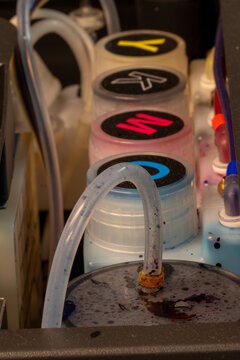 Refill color tanks on dtf textile printer. Printer ink supply system showing four primary color tanks.