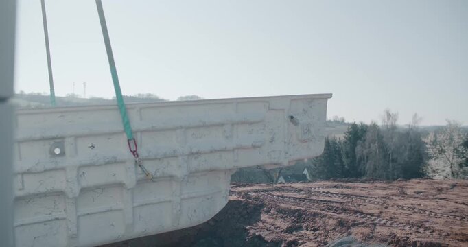 Precast concrete element suspended on lifting straps over muddy