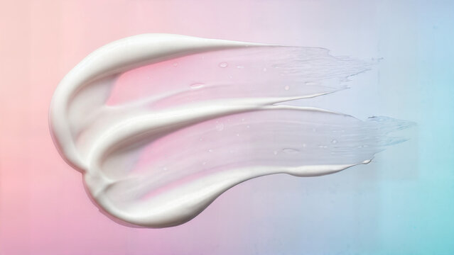 White cosmetic cream smear with translucent gel texture on colorful pink and blue gradient background for skincare product marketing and beauty therapy concept.
