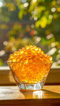 Golden honey caviar beads are clustered together inside a geometric glass bowl reflecting soft afternoon light from a nearby window.