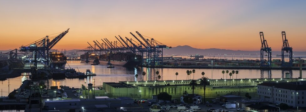 LOS ANGELES, CA, USA - AUGUST 14, 2026: Container ships docked under gantry cranes at the Port of Los Angeles during sunrise